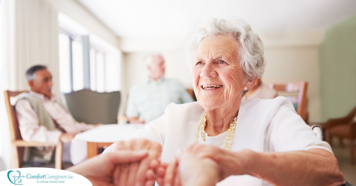 Happy senior-aged woman holding hands and smiling in nursing home.